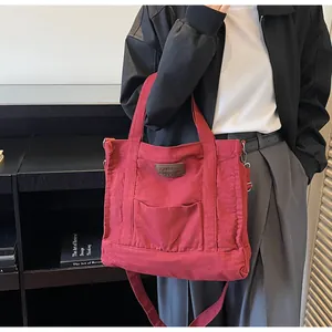 Detail view of burgundy canvas tote bag with front pocket and adjustable shoulder strap