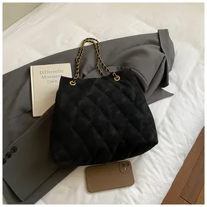 Detail van zwarte gewatteerde shopper met gouden ketting op een grijze blazer