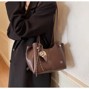 Detail view of large brown leather tote bag with stylish ice cream charm accessory