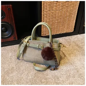Olive green bucket bag featuring leather-fabric stitching and a brown plush ball charm