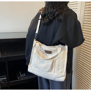 Detailed shot of white canvas tote bag worn by a model in a cozy indoor setting