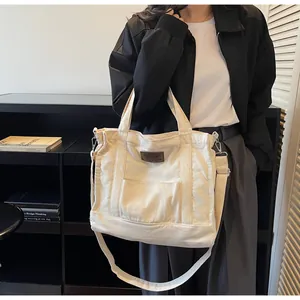 Detailed macro view of cream canvas tote bag with brown leather patch and dual straps