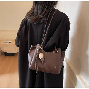 Detail of dark brown leather tote with thin straps, rope knot and ice cream charm