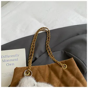Detail van bruine gewatteerde tas met gouden ketting en wit pluche konijnenhangertje