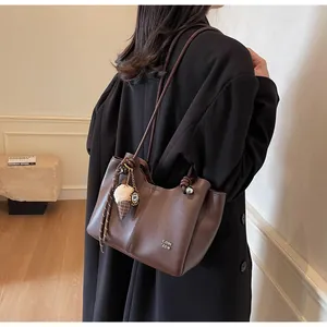 Detail of dark brown leather tote bag with unique knotted strap and ice cream charm