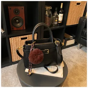 Macro shot of black bucket bag featuring woven texture and a plush pompom charm detail