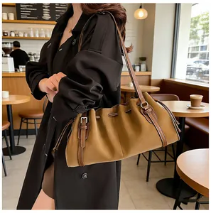 Detalle del bolso de hombro en cuero caqui con diseño plisado, cordón y hebilla metálica