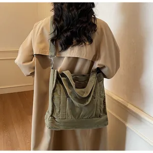 Detail of army green canvas tote bag with brown leather label and wide shoulder strap