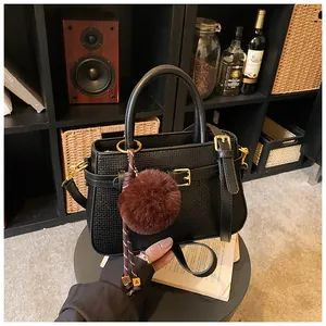 Close-up of black textured bucket bag with fur pompom and vintage hardware detail