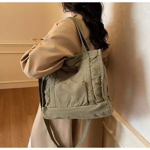 Canvas tote bag in army green showing large capacity and crossbody strap on a model