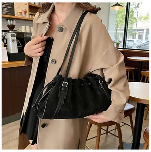 Detalle de un bolso nube negro plisado con cordón y correa ajustable en una modelo