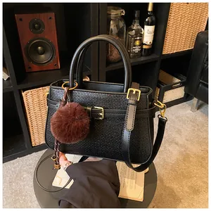 Detail of black croc-embossed bucket bag with gold hardware and plush charm