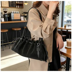 Detalle de bolso tote de ante negro con diseño plisado y cordón en una cafetería