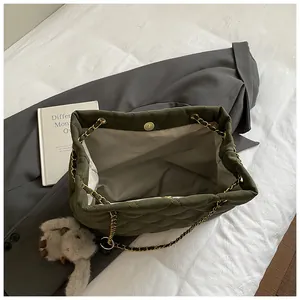 Detail van olijfgroene gewatteerde tas met magneetsluiting en konijnenhanger