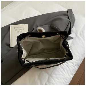 Detail van de gewatteerde zwarte draagtas met magneetsluiting en gouden kettingband