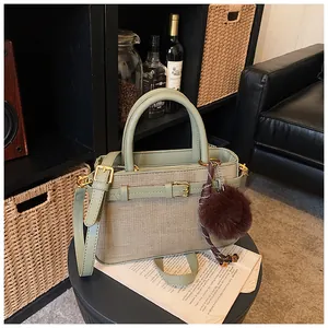 Detail of green leather bucket bag with woven panel and brown faux fur pompom charm