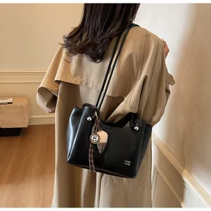 Detail of black leather tote bag with ice cream charm and Con Trdm logo on trench coat