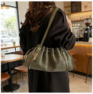 Detalle del bolso de hombro plisado verde oscuro con cordón y hebilla de correa metálica