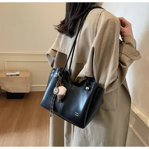 Close-up of black tote bag with vertical stitching and plush ice cream charm accessory