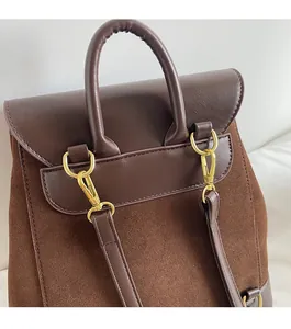 Close-up of golden metal hooks and matte leather stitching on a brown backpack