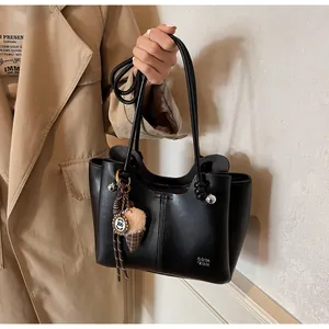 Detail of black leather tote bag with ice cream charm and metal ball accents on model