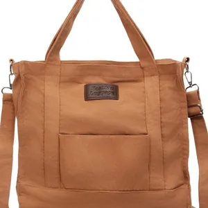 Brown canvas tote bag with adjustable shoulder strap and leather tag shown on white background