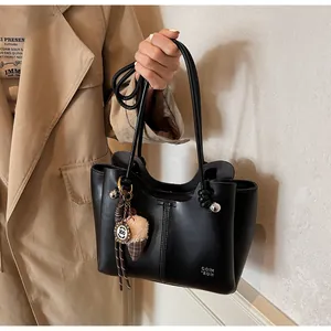 Detail of black leather tote bag with ice cream plush charm and precise stitching