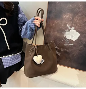 Detail of dark brown faux suede tote bag with white plush heart charm and stay story label