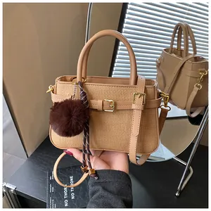 Detail of light brown woven bucket bag featuring smooth leather handles and plush charm