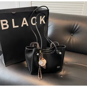 Close-up of black leather tote bag with ice cream charm and vertical stitching details