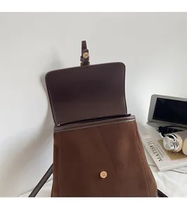 Detail of a brown suede backpack showing the secure gold magnetic snap closure design