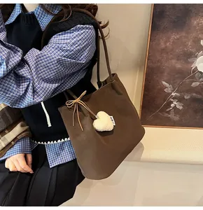 Detail view of coffee suede tote bag with leather bow and plush heart charm on the side