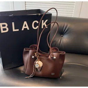 Detail of dark brown tote bag with ice cream charm and knotted shoulder strap