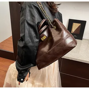 Close-up of quilted dark brown bucket bag with vintage gold clasp and chain strap