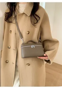 Detail shot of taupe pebbled leather handbag styled with a camel winter wool coat