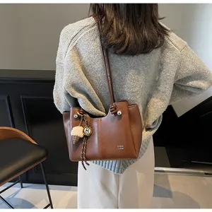 Brown leather tote bag detail with letter print and decorative ice cream pendant charm