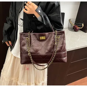 Detail of burgundy quilted tote bag with golden twist lock and chain strap on a model