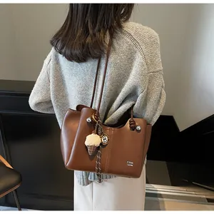 Brown leather tote bag featuring a cute ice cream charm and branded detail on the side
