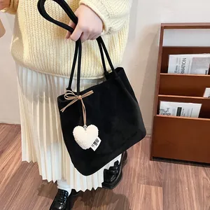 Black suede tote bag with plush heart charm and bow on minimalist autumn shoulder bag