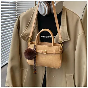 Detail of khaki woven texture bucket bag with faux fur pompom and stylish tassels