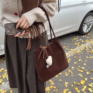 Brown suede tote bag with heart charm shown in an autumn street setting with ginkgo leaves