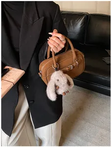 Detail of vintage brown Boston bag with a cute plush rabbit pendant and metal hardware