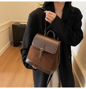 Detail of vintage brown suede backpack featuring leather trim and metallic buckle closure
