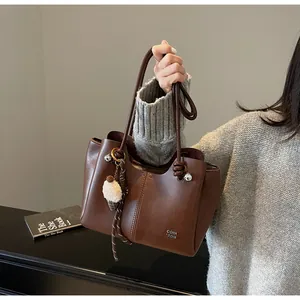 Close-up of large dark brown tote bag with metal branding and knotted handle detail