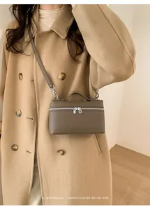 Close-up of a minimalist dark taupe box bag featuring silver zippers and lychee leather