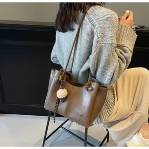 Detail of a large brown tote bag with leather texture and creative ice cream charm