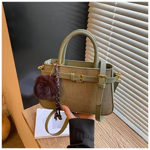 Detail of sage green textured bucket bag showing leather handle and gold metal hardware