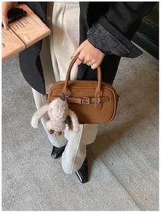 Detailed shot of a vintage brown leather square handbag with a cute plush bunny charm