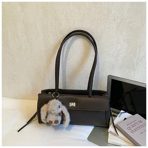 Close-up of brown leather bag with metal twist lock and a grey plush rabbit charm