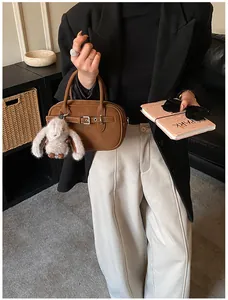 Detail of vintage brown leather handbag with buckle strap and plush bunny charm accessory